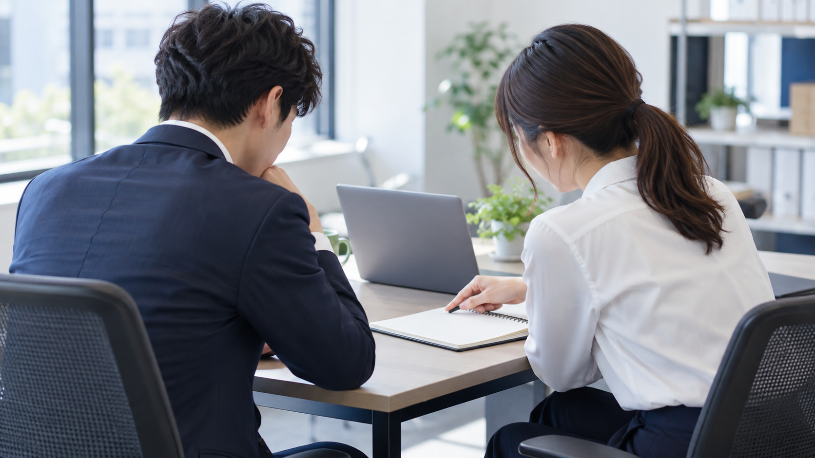 同僚二人がパソコンの横で相談しているオフィス
